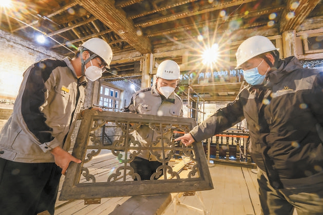 在东城区西晓市街同兴和木器店旧址修缮现场，京诚集团老工匠刘京生（右）向年轻学员传授技艺